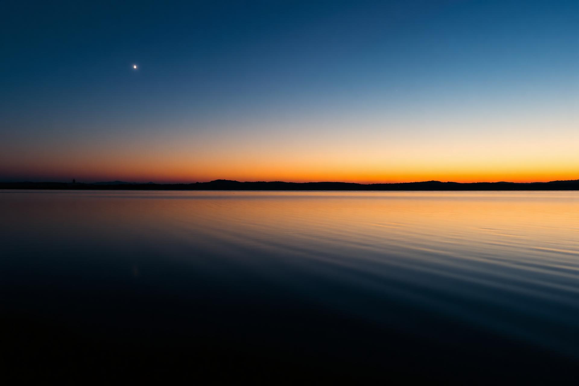 Água calma refletindo luz dourada ao entardecer